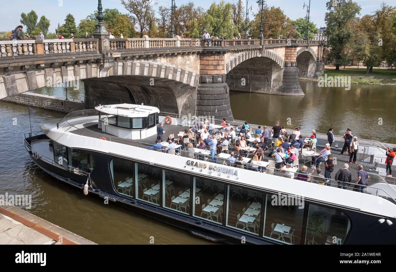 Moldau, Prag, Tschechische Republik, ein Sightseeing Riverboat mit Touristen unter einer gewölbten Brücke an der Moldau geht. Stockfoto