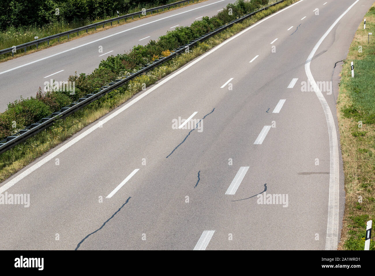 Zufahrt zu einem kleinen deutschen Autobahn mit Reifenspuren und Schäden Stockfoto
