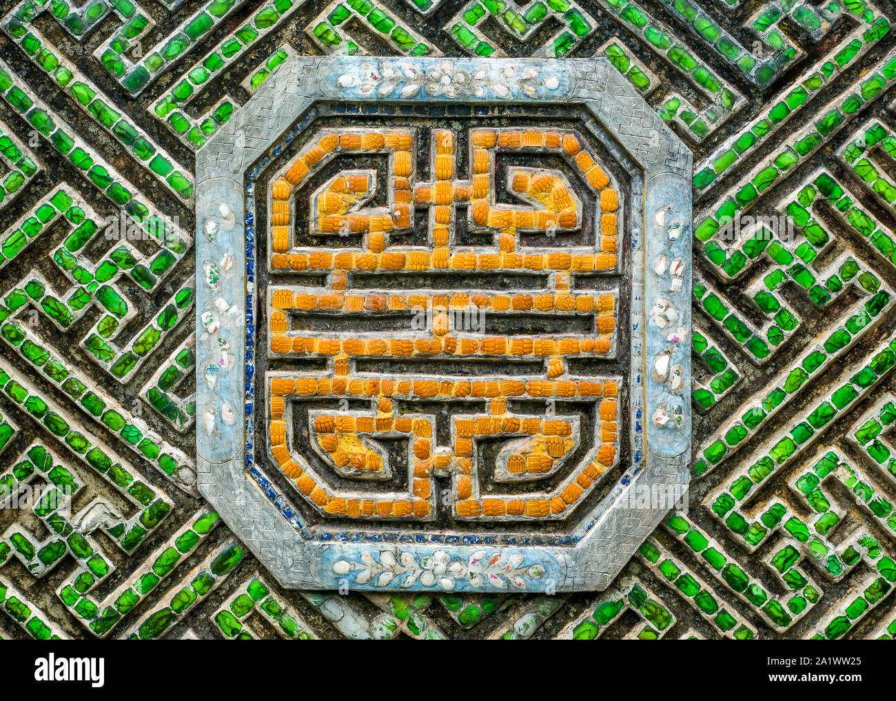 Traditionelle bunte Mosaik Verzierung mit buddhistischen Symbole aus Edelsteinen in leuchtendem Orange und Grün Stockfoto