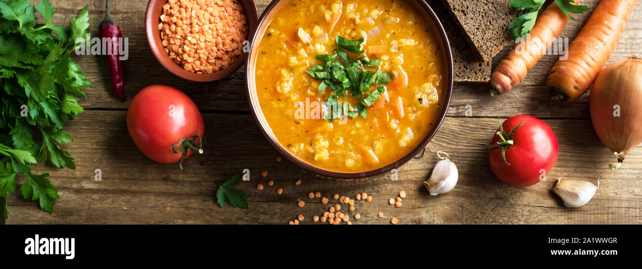 Rote Linsensuppe auf hölzernen Hintergrund, Ansicht von oben, Banner. Traditionelle türkische oder arabische Linsen und Gemüse würzige Suppe, gesunde vegane Ernährung. Stockfoto