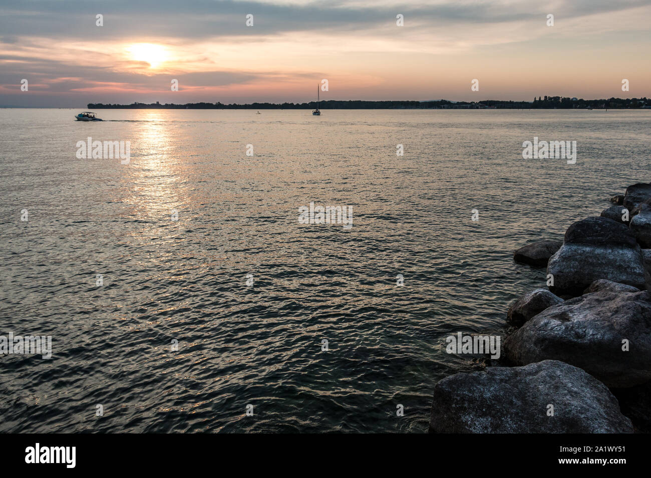 Schwarz Boote und einem kleinen schwarzen Landzunge in das Wasser und einen goldenen Sonnenuntergang Stockfoto