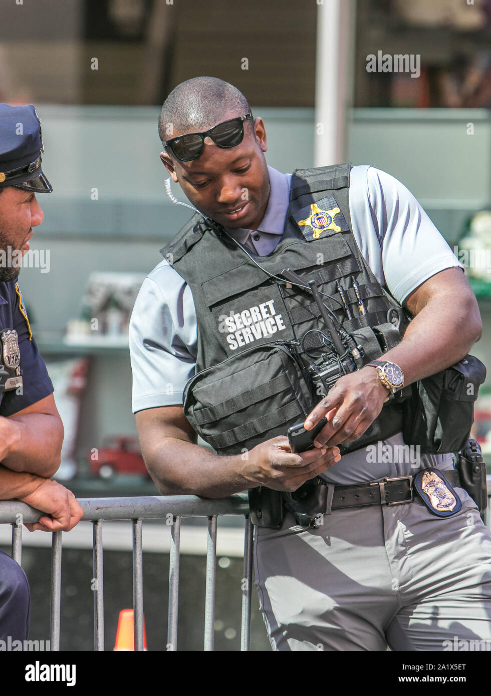 New York City, 27.9.2019: Tall Secret Service Agent sucht bei seinem Telefon bei einer Polizeikontrolle in Manhattan während der UN-Vollversammlung. Stockfoto