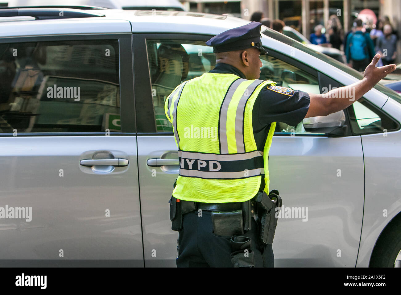 New York City, 27.9.2019: NYPD Officer das Tragen einer Warnweste über seine Uniform ist die Kommunikation mit einem Kraftfahrer und lenkt den Verkehr Manhattan. Stockfoto