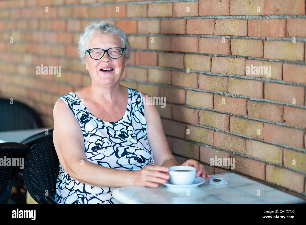 Alte Frau Getränke Kaffee und lächelnd in die Kamera. Stockfoto