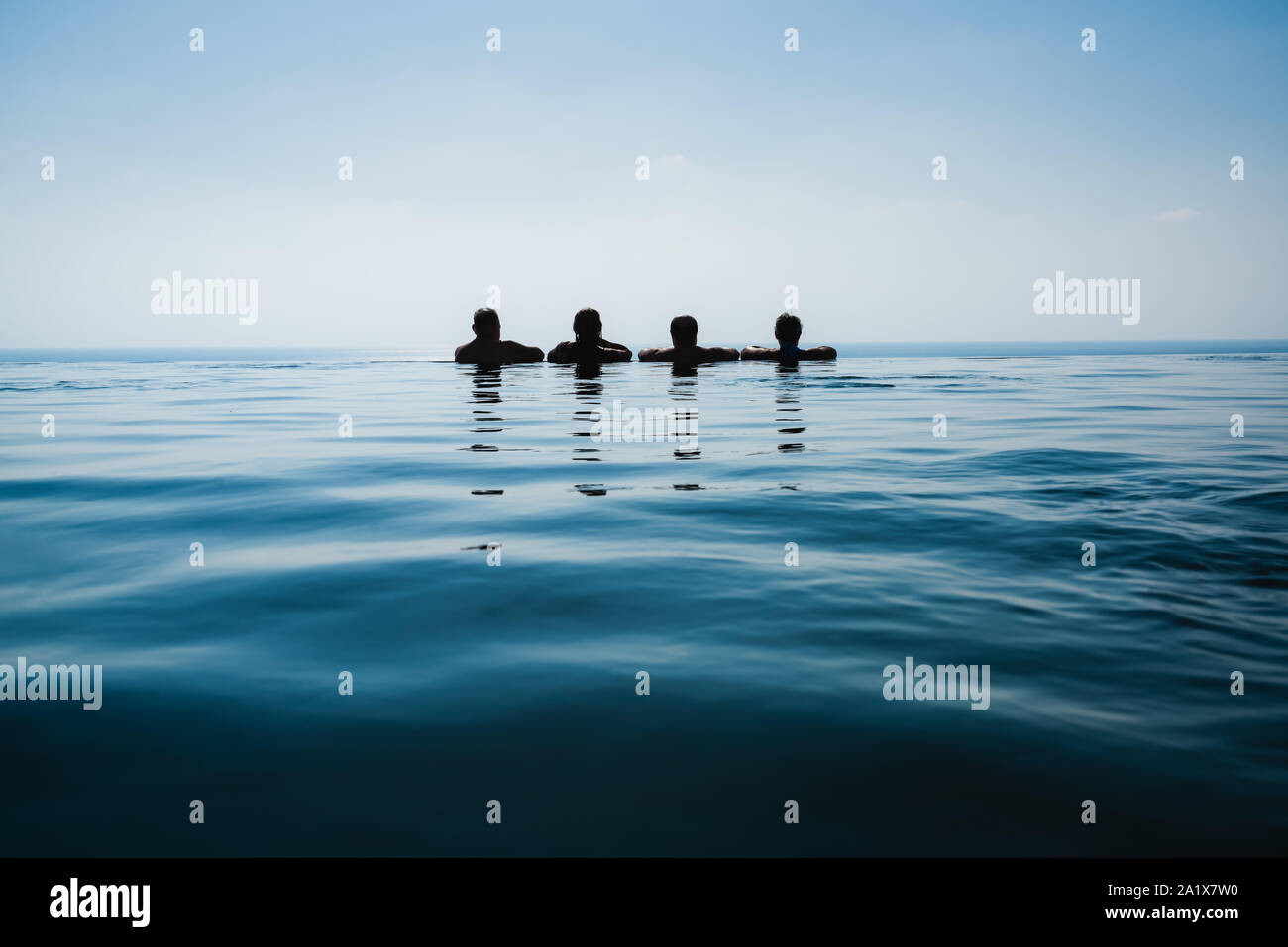 Freunde im Pool schwimmen gegen den blauen Meerblick Stockfoto