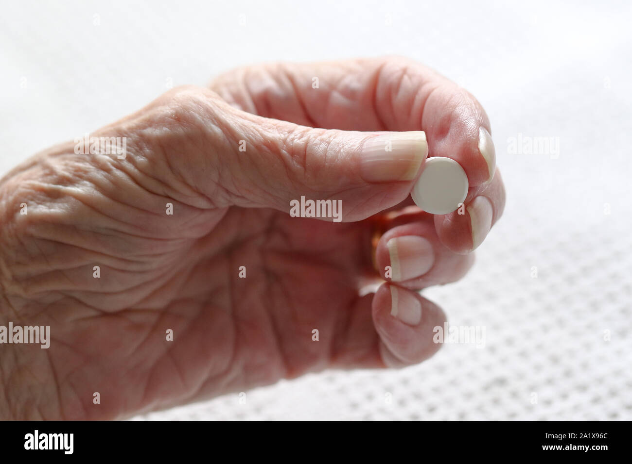 Eine ältere Damen Hand an der Parkinsonschen Krankheit leidet, die eine Pille. Stockfoto