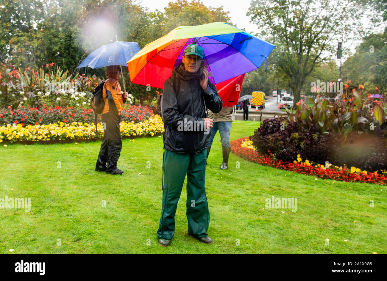Ventilator verwendet große Regenbogen Regenschirm zum Schutz vor Regen am letzten Tag der UCI Rad WM, Harrogate, UK, 29. September 2019 Stockfoto