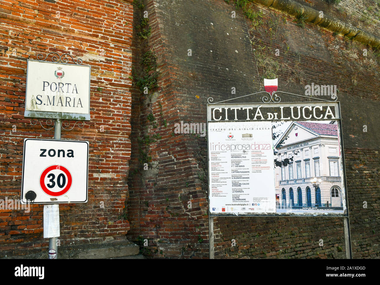 Nahaufnahme der Name sign von Porta Santa Maria City Gate und einer städtischen Zeichen mit dem Programm der Giglio Theater, Toskana, Italien Stockfoto