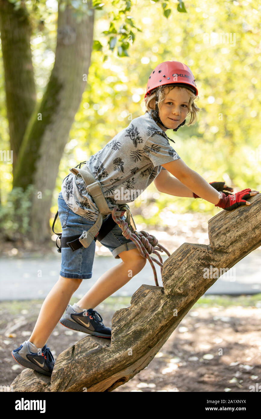 Klettergarten, Kletterkurs, Junge, 9 Jahre alt, mit Helm und Klettergurt, auf einem Kletterkurs in einem Wald, Stockfoto