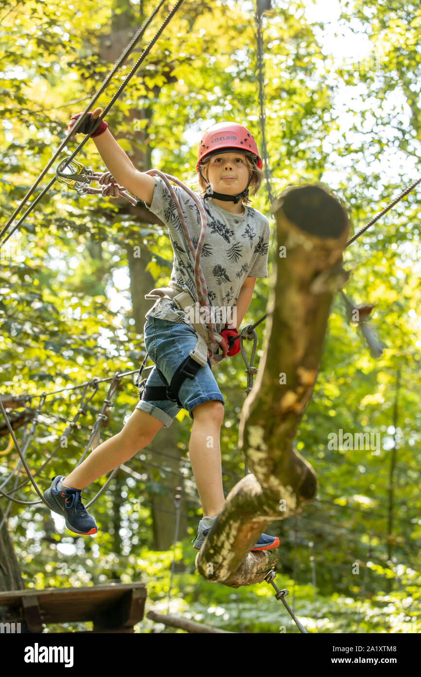 Klettergarten, Kletterkurs, Junge, 9 Jahre alt, mit Helm und Klettergurt, auf einem Kletterkurs in einem Wald, Stockfoto