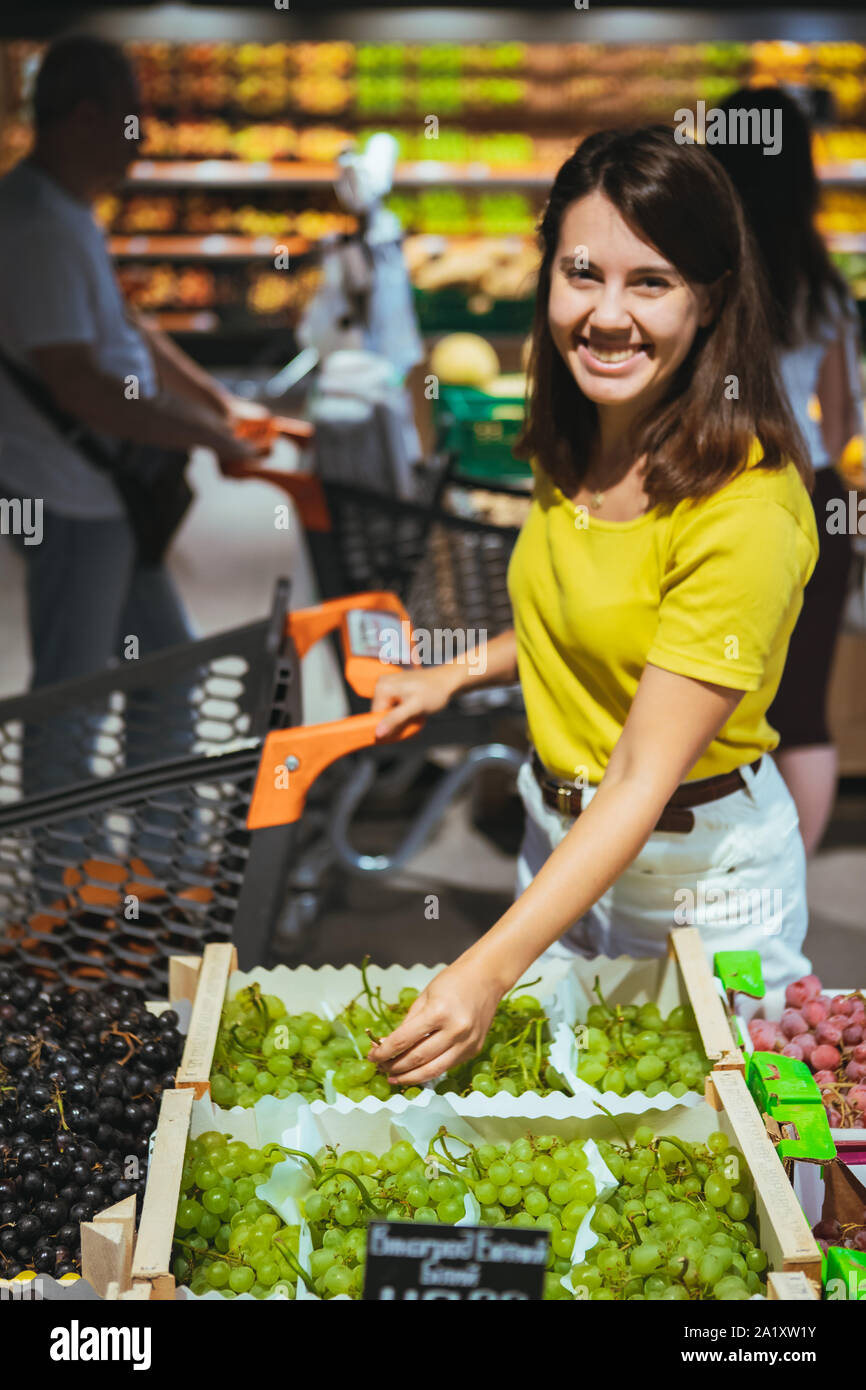 Frau kauft Trauben in Store Stockfoto