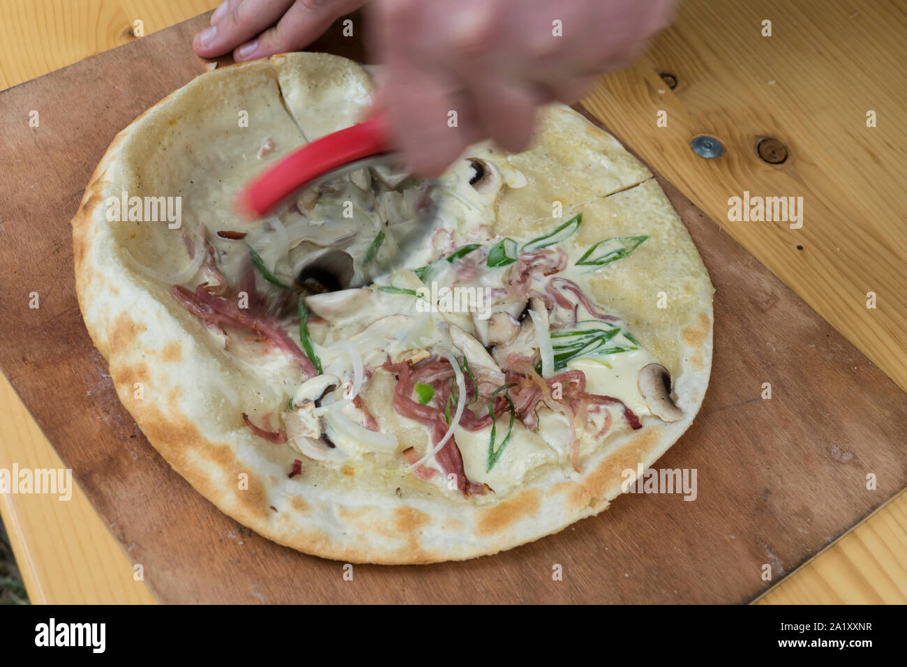 Flammkuchen beim Zubereiten mit Speck, Zwiebeln und Creme fresh Stockfoto