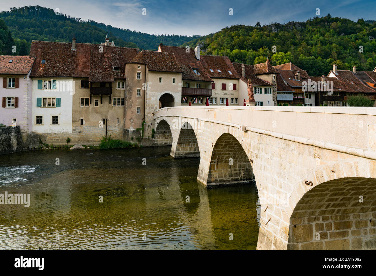 Saint-Ursanne, Jura/Schweiz - vom 27. August 2019: historische Steinbrücke führt zum Tor und malerischen Dorf Saint-Ursanne Stockfoto