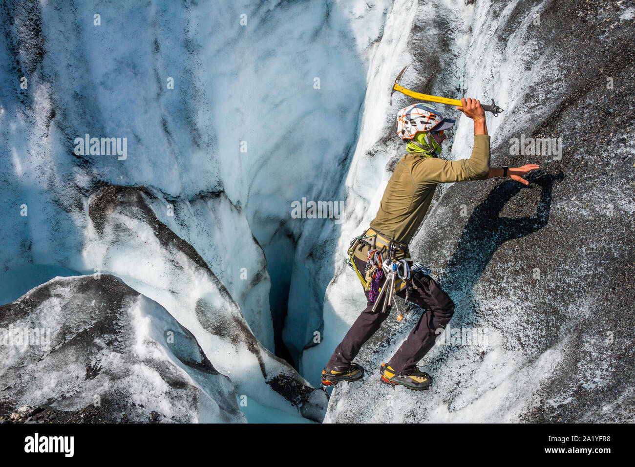 Ein ice Climber free soloing Neben einer Eishöhle, auf der Suche nach einem sicheren Ort ein Seil in die Höhle weiter zu befestigen. Stockfoto