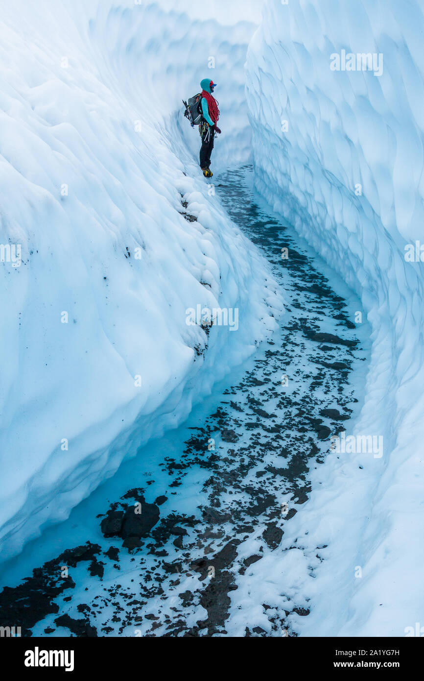 Eine junge Frau, die Kunden rund um den Matanuska Gletscher hält in einem Canyon geschnitten aus dem Eis warten auf Ihre Kunden. Sie trägt ein Kabelbaum, Rucksack ein Stockfoto