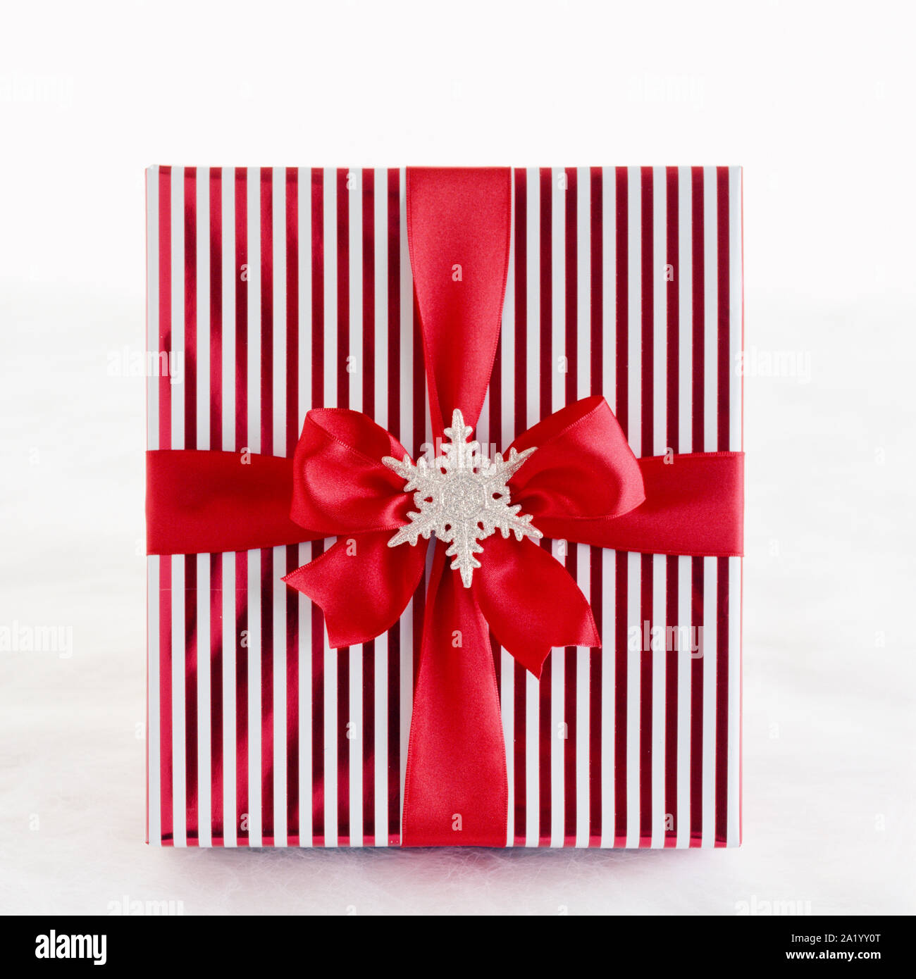 Rot-weiß gestreifte Weihnachtsgeschenk präsentieren mit metallischen Geschenkpapier, satin schleife und Silber Glitzer Schneeflocke Dekoration auf weißen backgroun Stockfoto