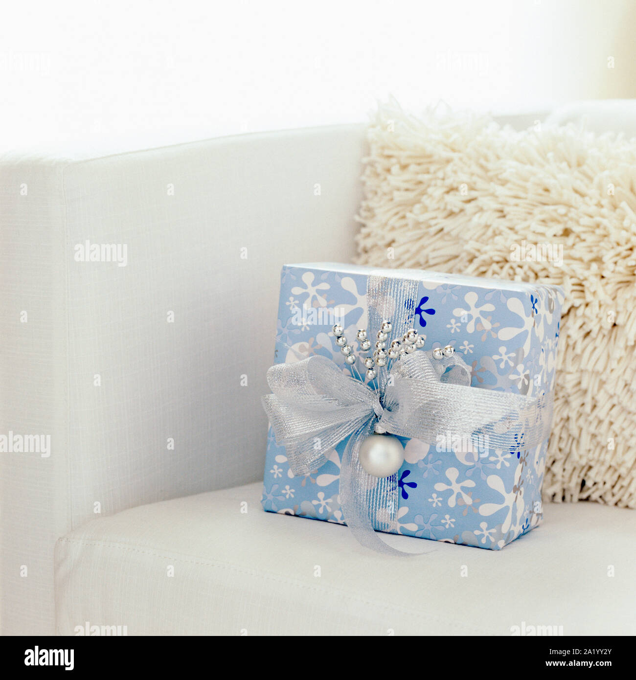 Weihnachten Geschenk vorhanden mit festlichen blaue und weiße Verpackung Papier in modernen Wohnzimmer Home Interior mit weißem Hintergrund. Selektiver Fokus auf Gabe. Stockfoto