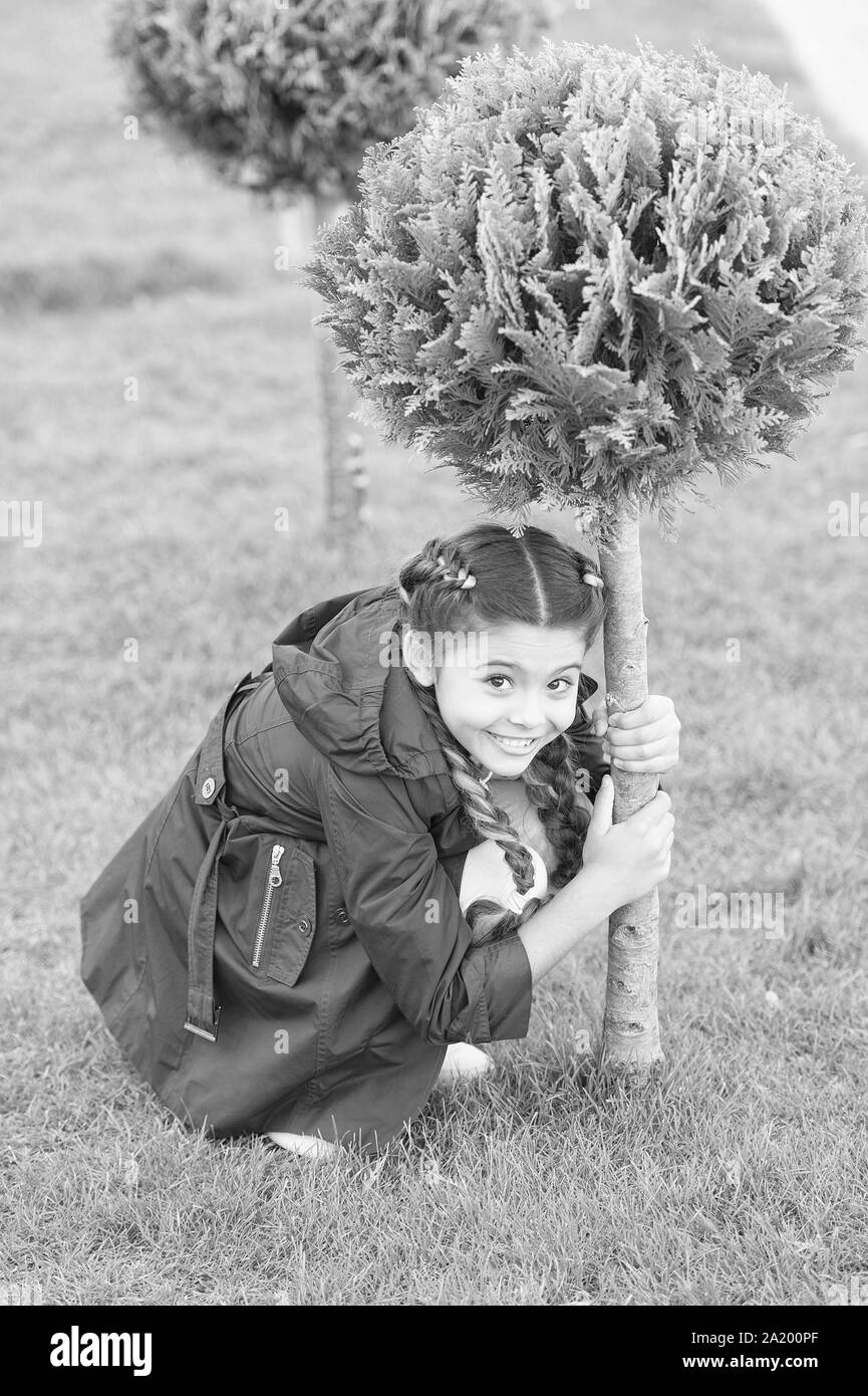 Verstecken spielen. Mädchen cute kid grünes Gras Hintergrund. Gesunde emotionale glückliches Kind Entspannung im Freien. Was macht Kinder glücklich. Mädchen Zöpfe Frisur entspannen. Gerne ausblenden Spiel im Freien. Stockfoto