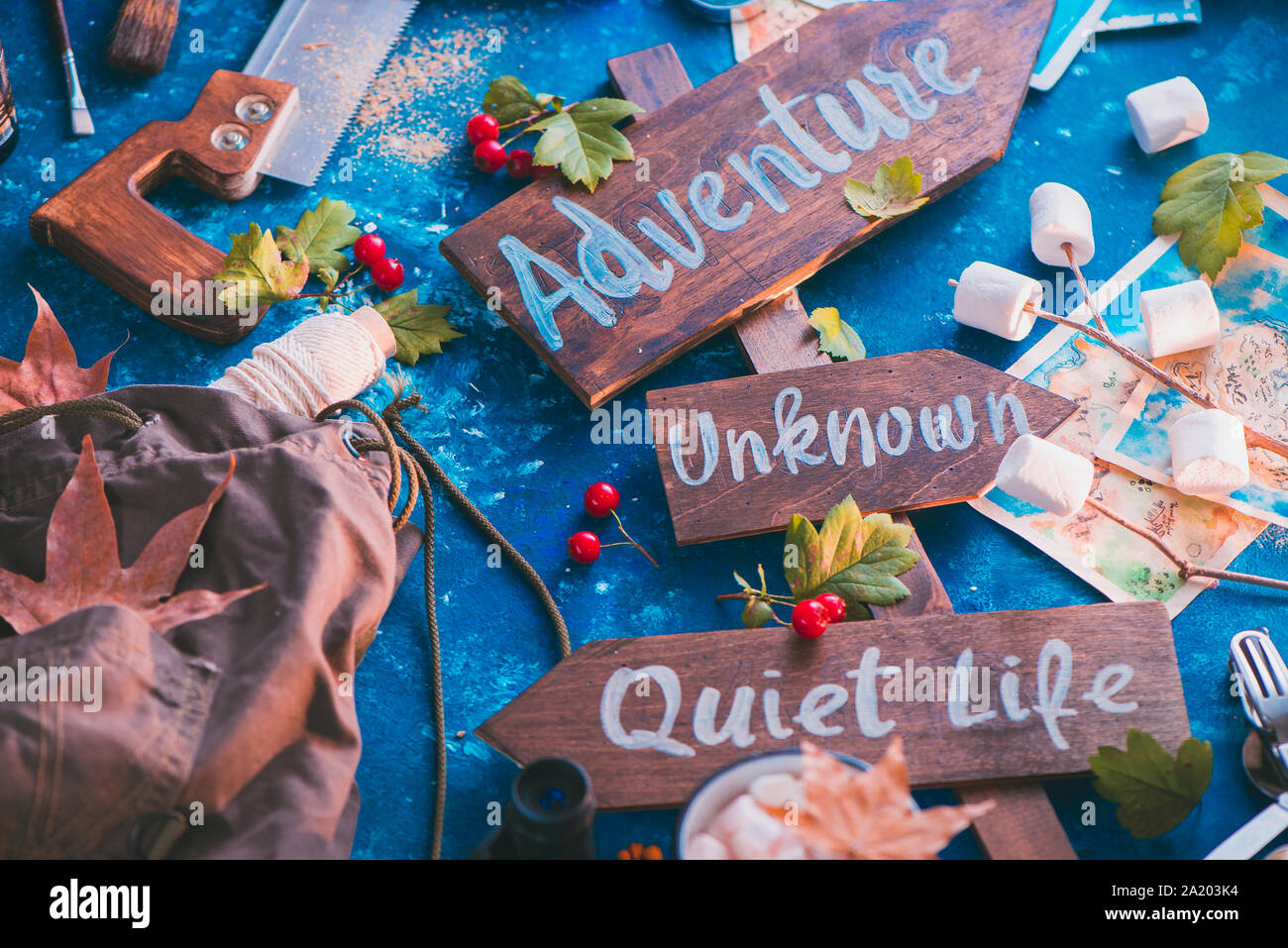 Schild mit Abenteuer, Unbekannte und ruhiges Leben. Travel Essentials kreativer Kopf mit Socken, Karten und Marshmallows, Fernweh Konzept Stockfoto