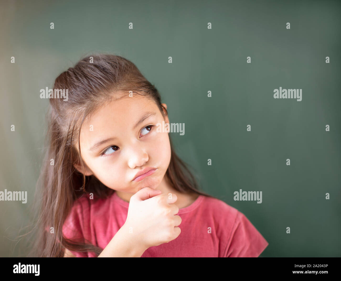 Kleines Mädchen stehend gegen Schiefertafel Hintergrund Stockfoto