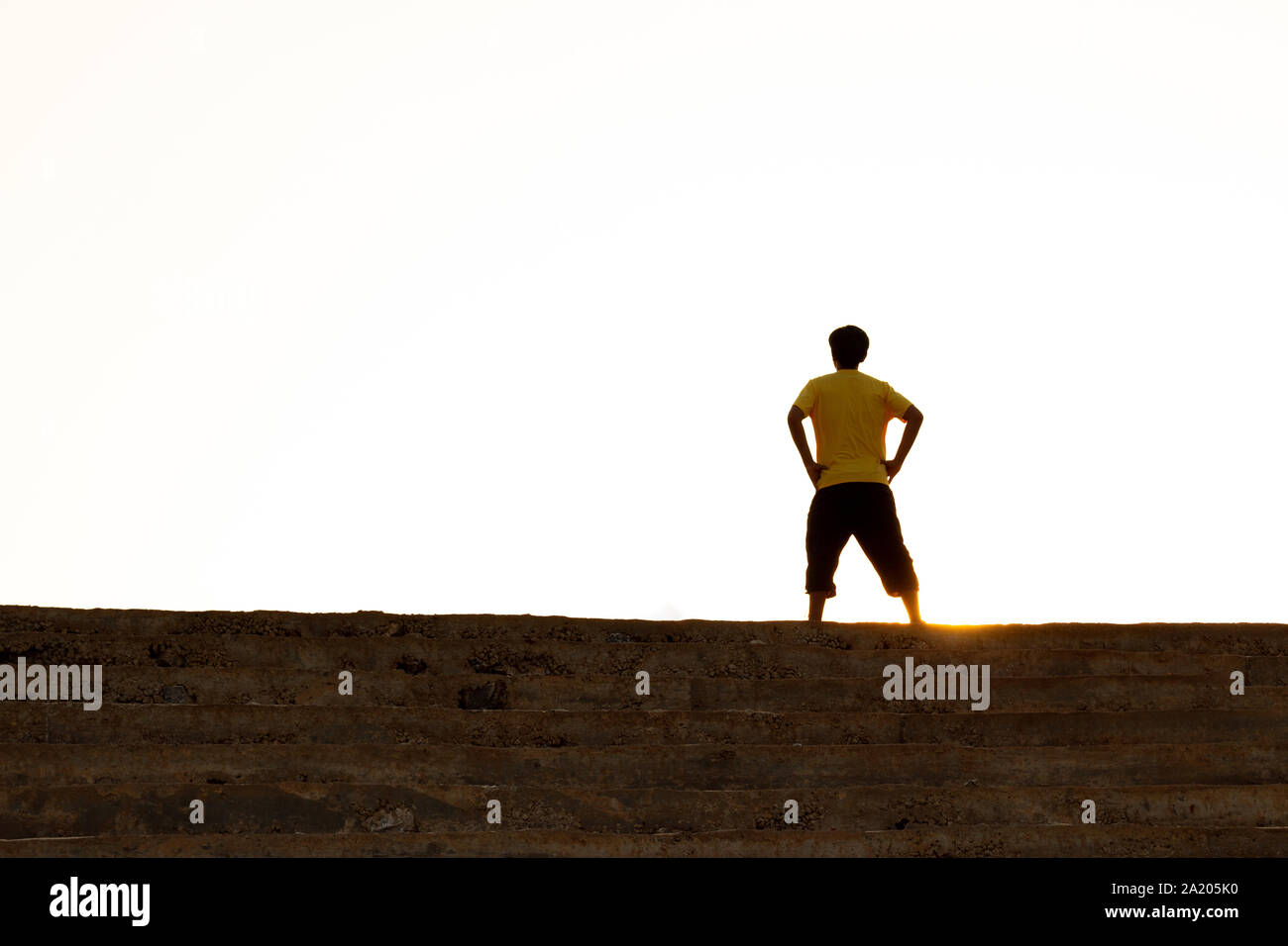 Der junge Mann am oberen Ende der Treppe zu den Sonnenuntergang Himmel, Ambitionen Konzept und erfolgreich. Stockfoto