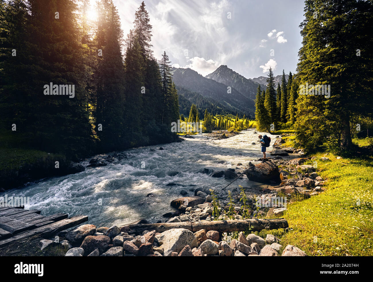 Touristische mit grossen Rucksack in der Nähe des Flusses am grünen Tal in Karakol Nationalpark, Kirgisistan Stockfoto