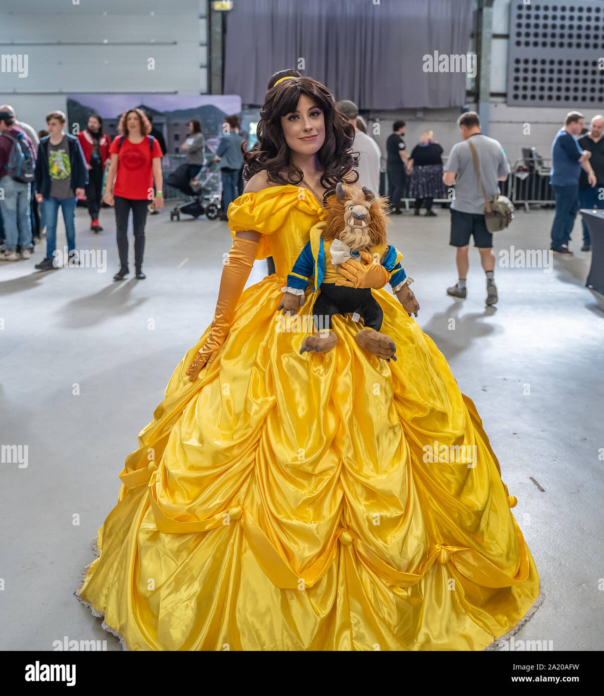 Eine junge und attraktive Lady in einem gelben Ball Abendkleid gekleidet wie die fiktive Figur Belle aus Die Schöne und das Biest Stockfoto