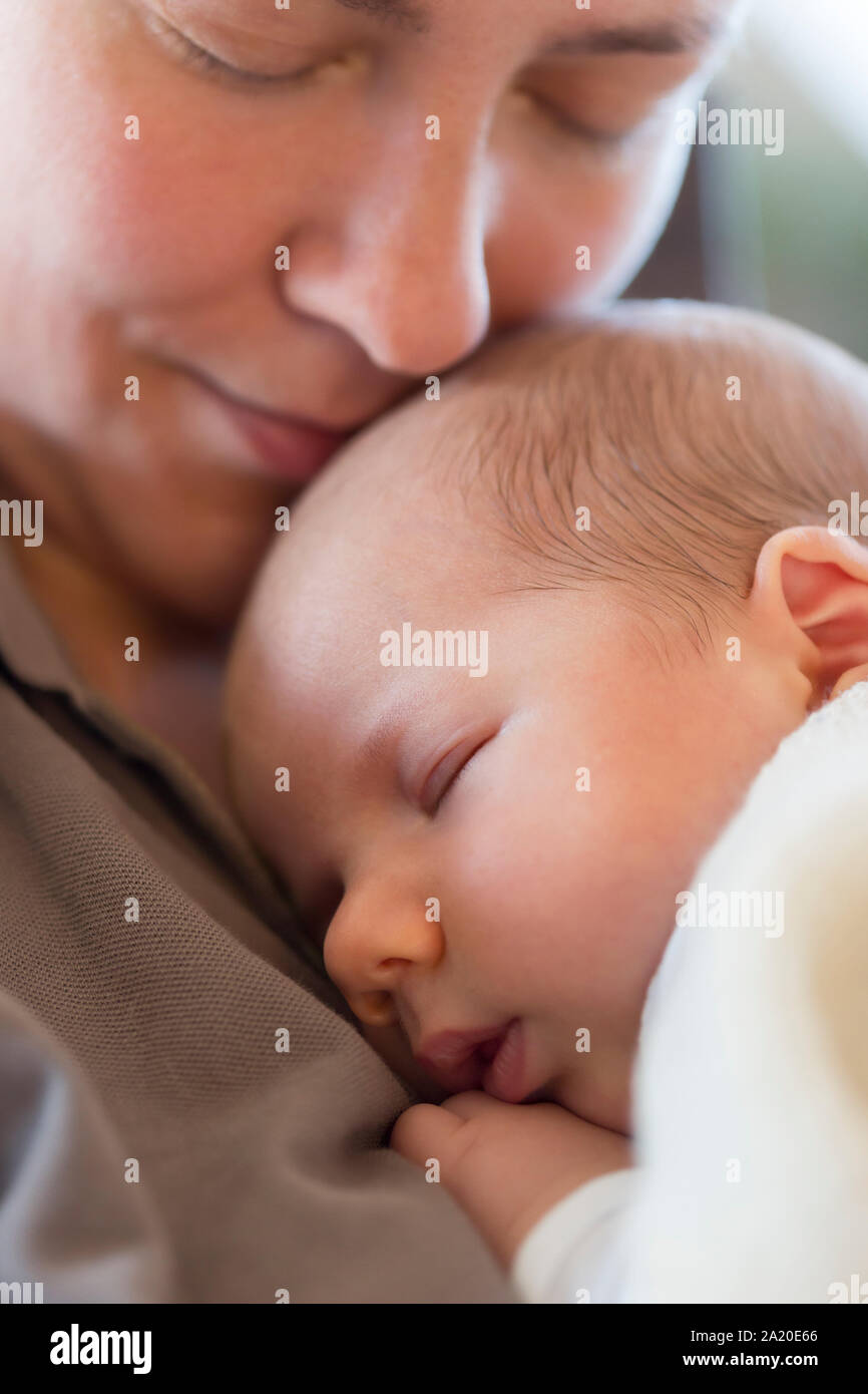 Mütterliche Zuneigung: Friedliche Baby schlafen auf der Mutter Brust. Stockfoto