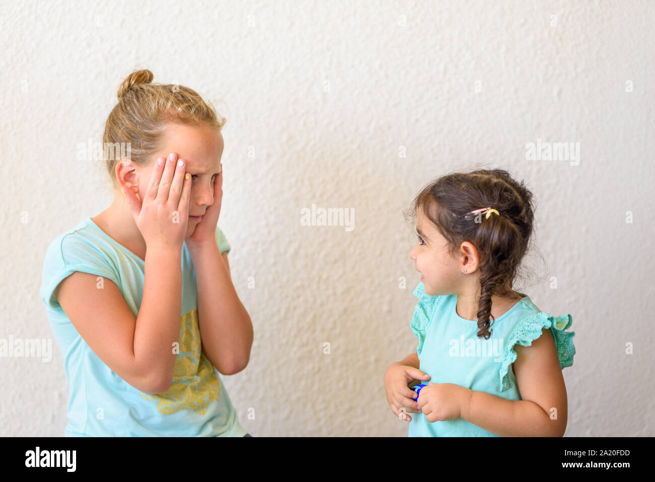 Schockiert jugendlicher Mädchen und ihr Kleinkind Schwester gegen den weißen Hintergrund. Emotionale entsetzt gemischten Rennen Kinder überrascht. Stockfoto