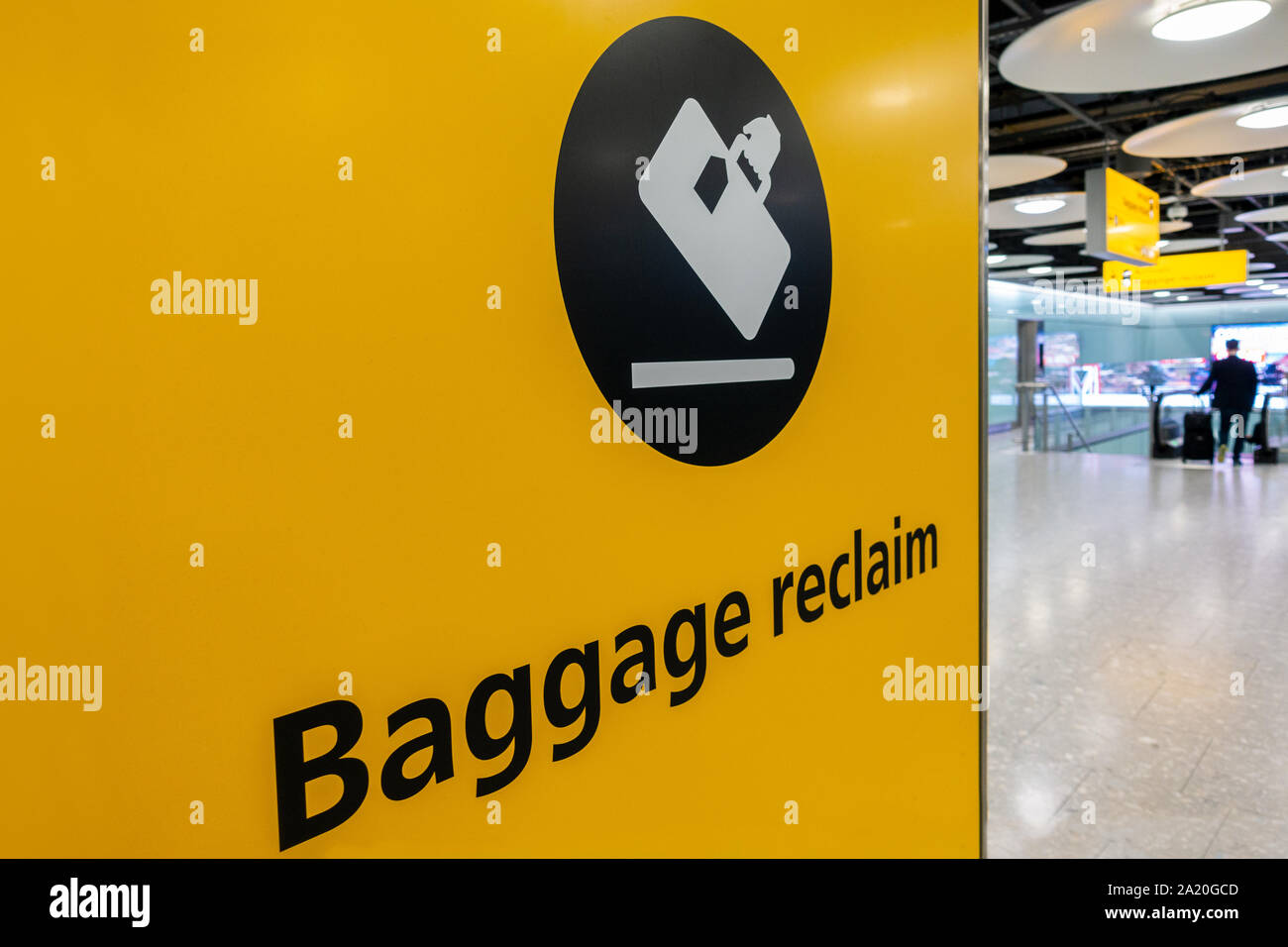 Gepäckausgabe unterzeichnen und Fahrgast mit rollenden Koffer am Flughafen Stockfoto