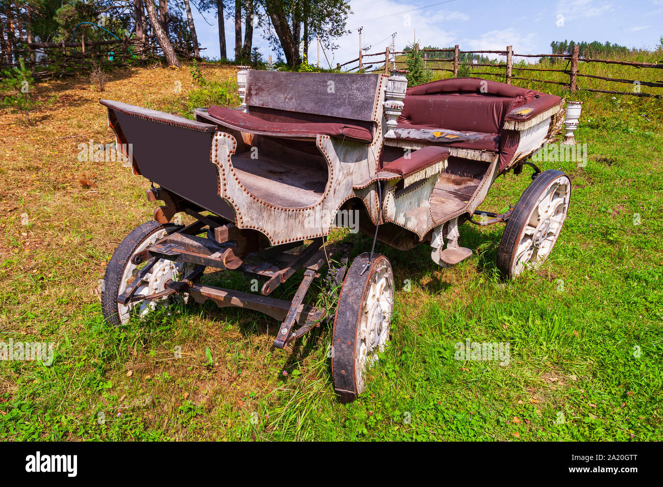 Einen alten Schlitten aus Holz mit großen Rädern ohne Pferd an einem Berghang auf grünem Gras. Retro und Vintage aus der Geschichte. Stockfoto