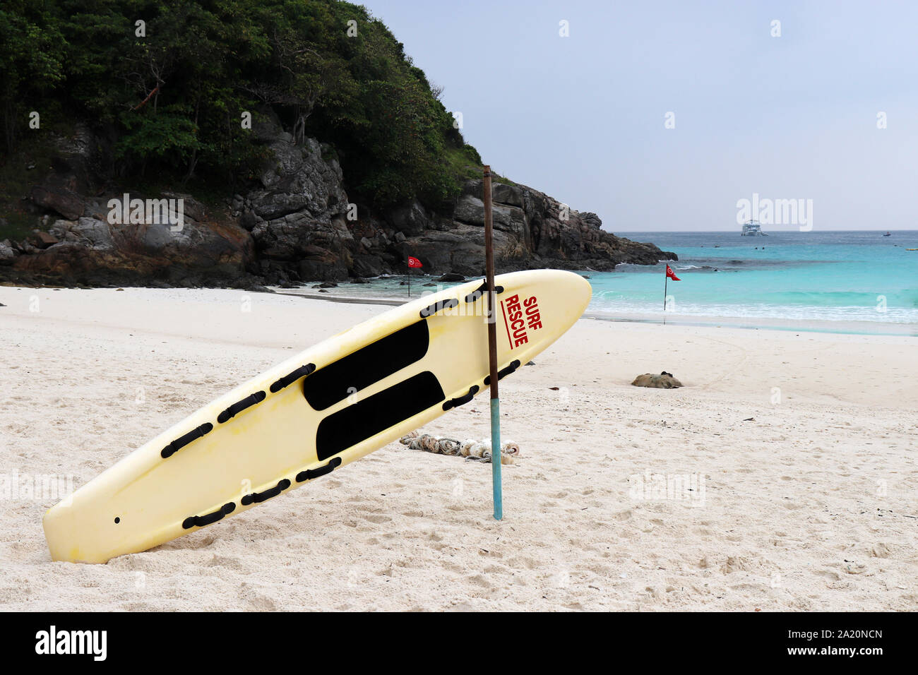 Surf rescue Board an einem tropischen Strand in einer malerischen Bucht mit roten Fahnen. Rettung von ertrinken in stürmischer See, Verbot von Schwimmen Stockfoto