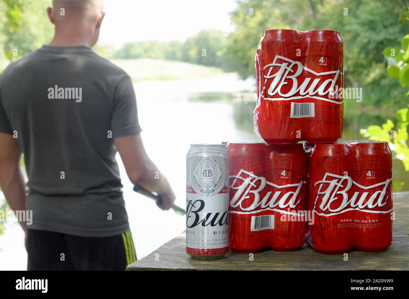 Kharkov, Ukraine - August 10, 2019: Budweiser Bud Bierdosen pack auf alten Tisch und Fischer am Fluss für den Hintergrund. Budweiser ist einer der beliebtesten Stockfoto