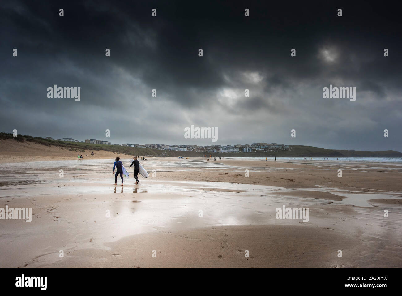 Surfer gehen über den Strand von Fistral als dunkle, dramatische Kühle herbstliche Wetter Ansätze in Newquay in Cornwall. Stockfoto