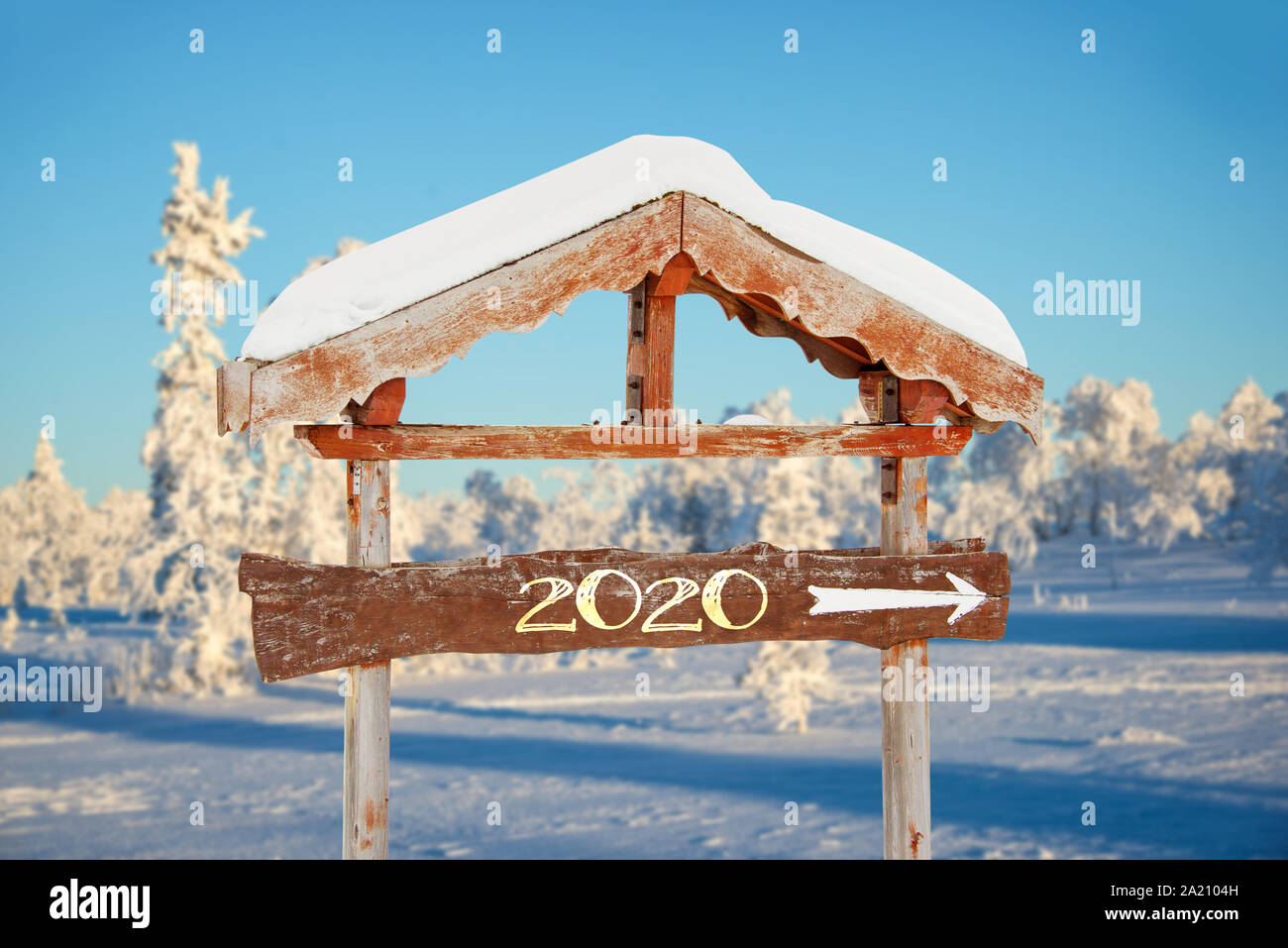 2020 auf einer hölzernen Richtung Zeichen, blauem Himmel und im Winter verschneite baum landschaft Hintergrund happy holiday seasons Neujahrsgrüße geschrieben Stockfoto