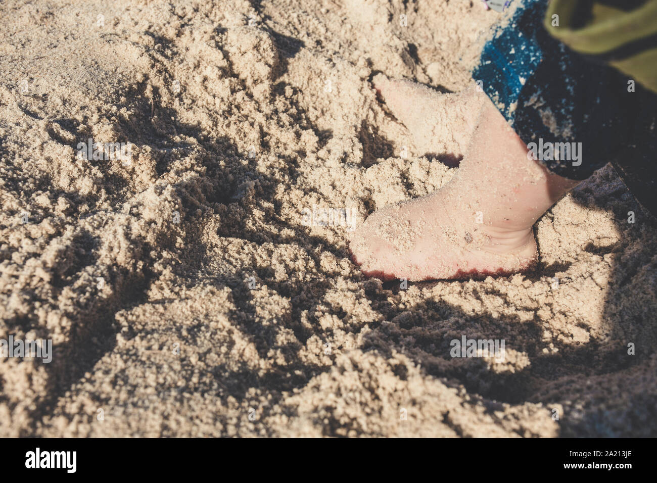 Baby Kleinkind erforscht das Leben auf dem Sandstrand. Füße für ein Kleinkind auf dem Sand. Konzept der Exploration, Reisen, und im Sommer Stockfoto