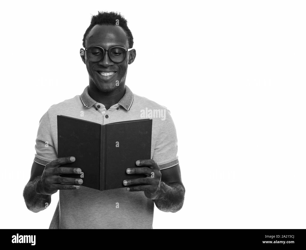 Junge glücklich afrikanischer Mann lächelnd, während Buch lesen Stockfoto