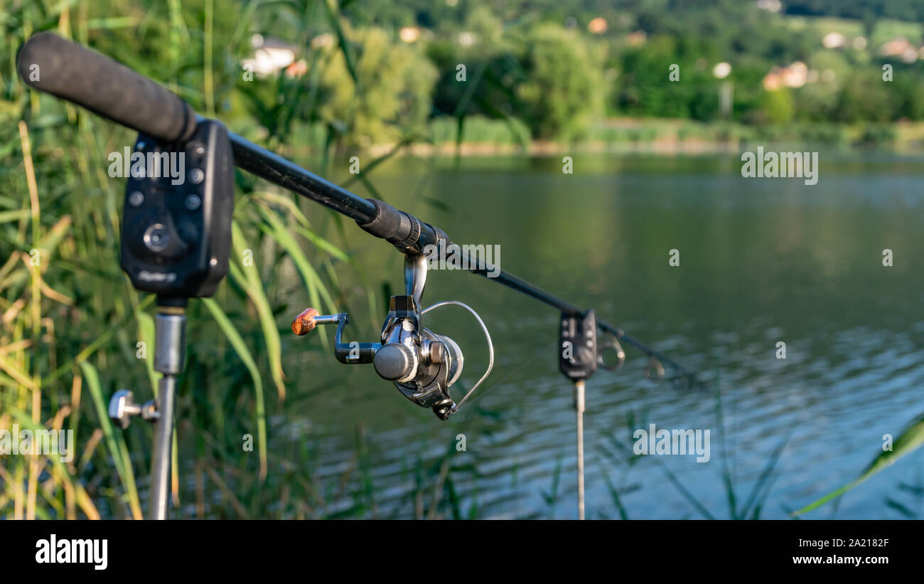 Nahaufnahme einer Haspel Angelrute auf eine Stütze im Hintergrund einen See und die Berge. Stockfoto