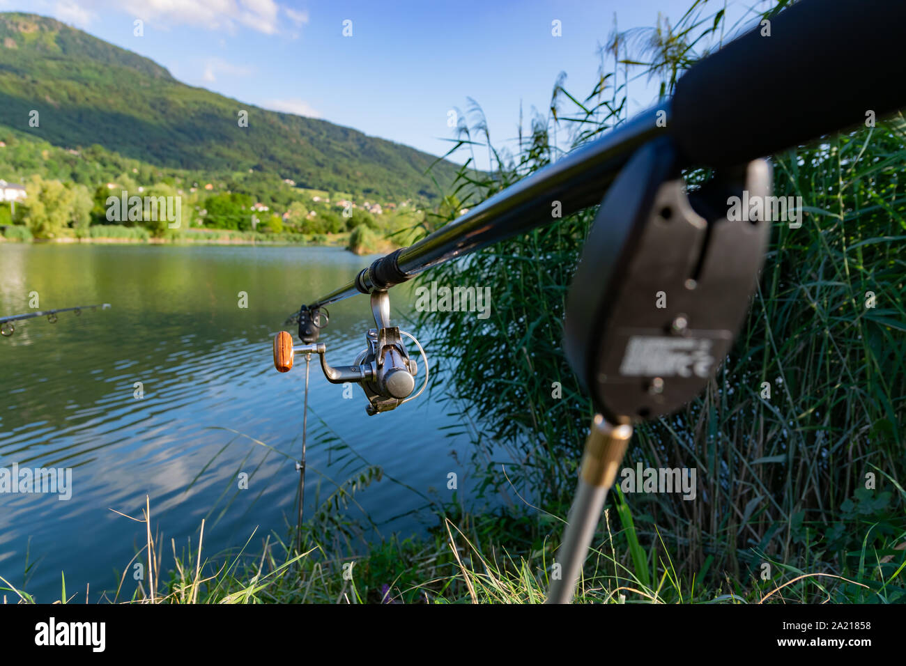 Nahaufnahme einer Haspel Angelrute auf eine Stütze im Hintergrund einen See und die Berge. Stockfoto