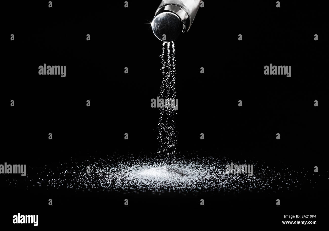 Salz Verschütten von Flüssigkeiten aus dem Salzstreuer in dünnen Datenströme auf einem schwarzen Hintergrund. Konzept Salzen/ Stockfoto