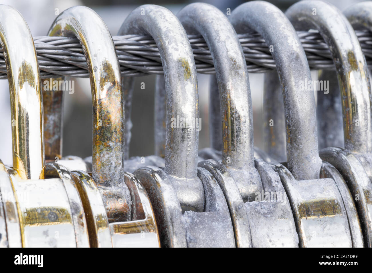 Herzförmige golden Vorhängeschlösser hängen an einem Stahldraht Nahaufnahme und Makro. Stockfoto