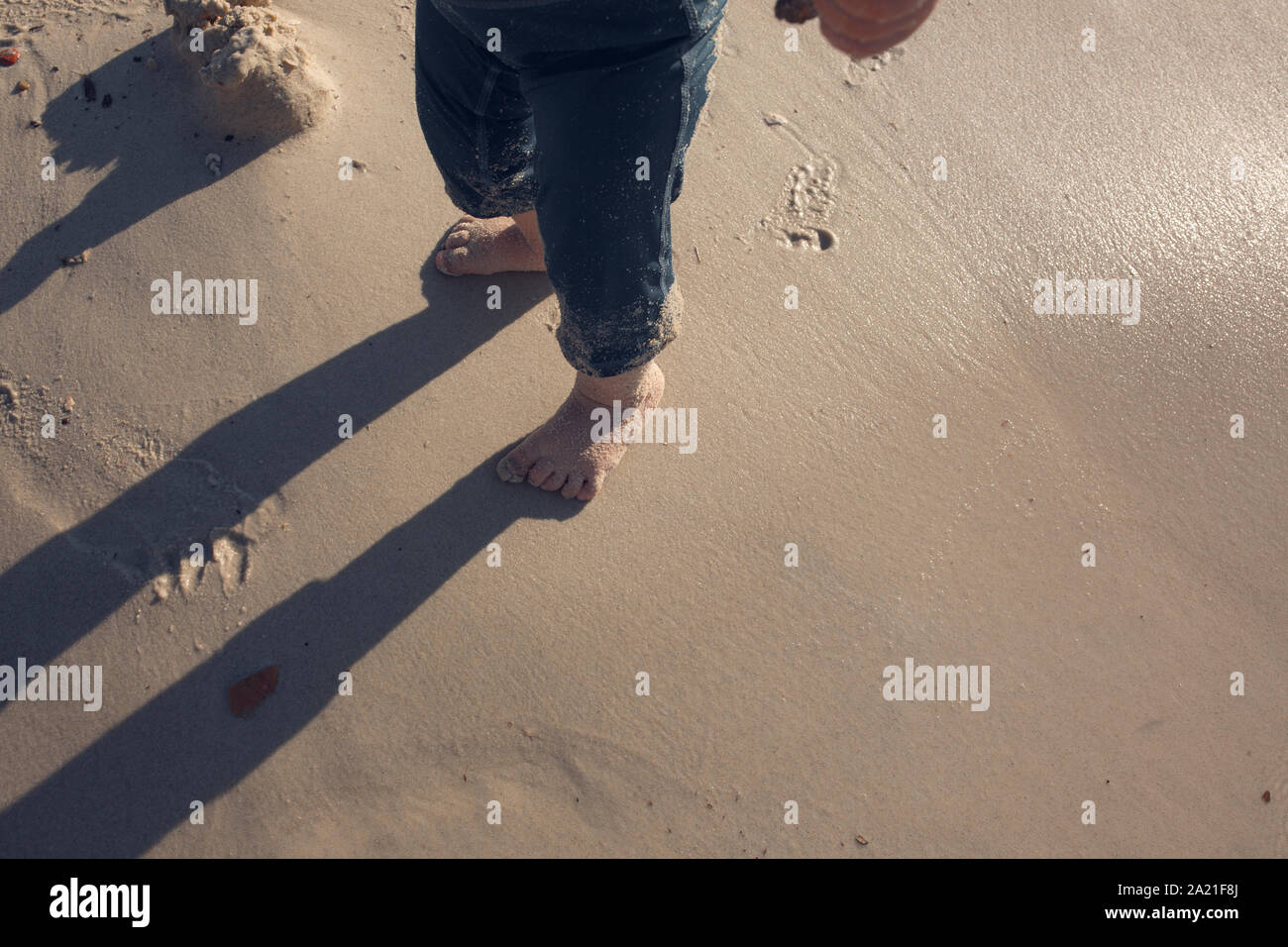 Baby Kleinkind erforscht das Leben auf dem Sandstrand. Füße für ein Kleinkind auf dem Sand. Konzept der Exploration, Reisen, und im Sommer Stockfoto