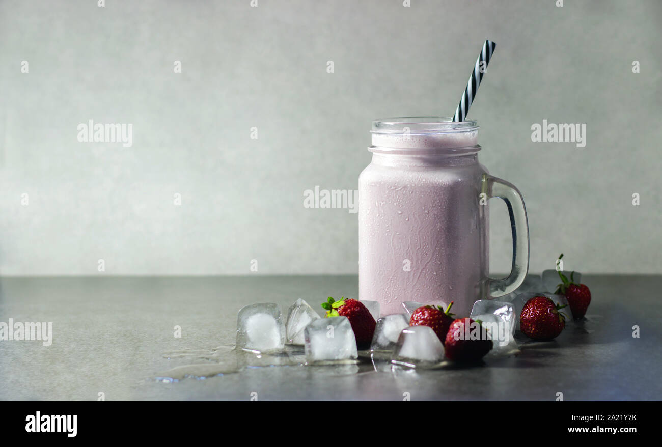 Erdbeer Milchshake, rosa Protein Drink mit Erdbeeren und Eis auf einem grauen Hintergrund. Kopieren Sie Raum, Ort für Text. Stockfoto