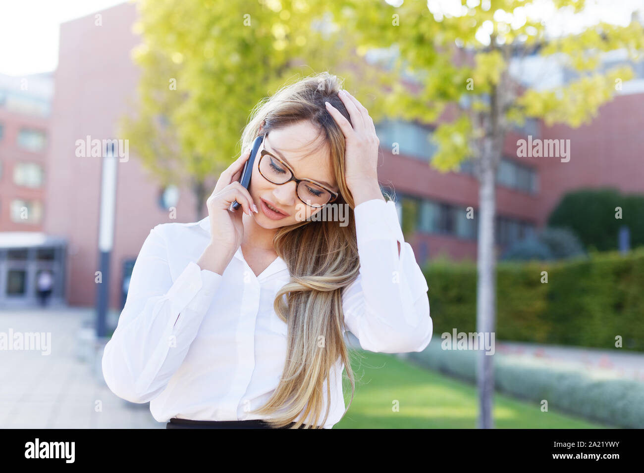 Blonde junge geschäftsfrau Kopfschmerzen während der Aufruf in Park Stockfoto