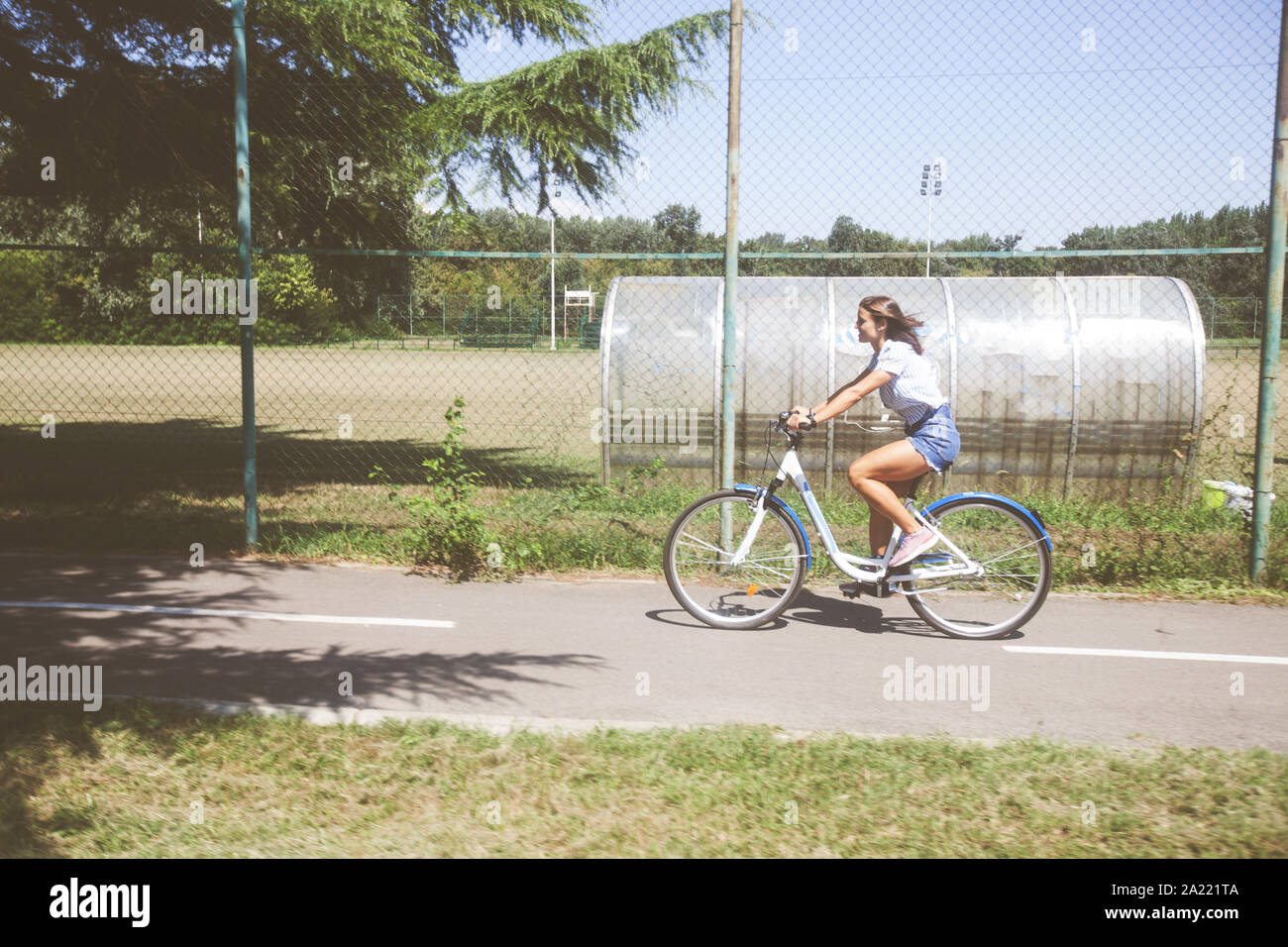 Portrait von Happy attraktive junge Frau in Jeans Shorts mit Fahrrad im Park im Sommer Tag. Stockfoto