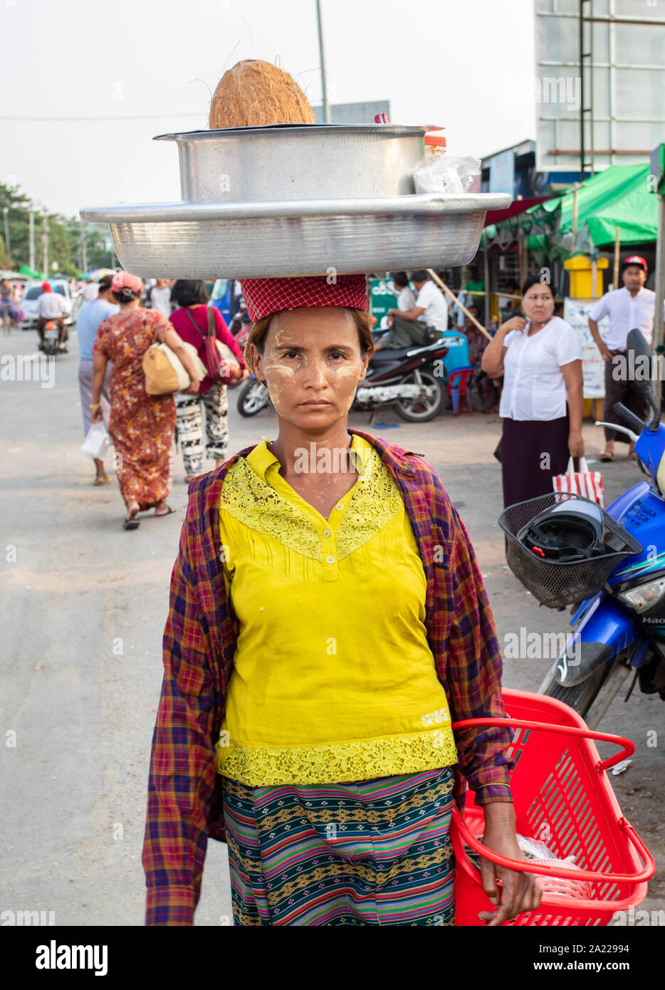 Frau trägt Gewicht auf dem Kopf. Straßenverkäuferin mit Schüssel auf dem Kopf. Stockfoto