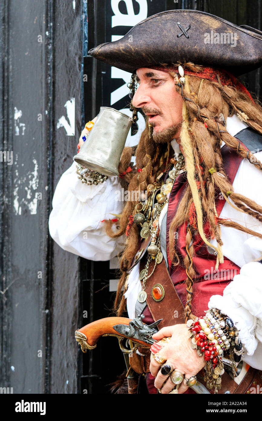 Piraten Tag in Hastings, Großbritannien. Reifer Mann verkleidet als Pirat  mit langen geflochtenen Haaren, nehmen einen Drink aus Silber Bier Tankard.  Von der Seite. Close Up Stockfotografie - Alamy