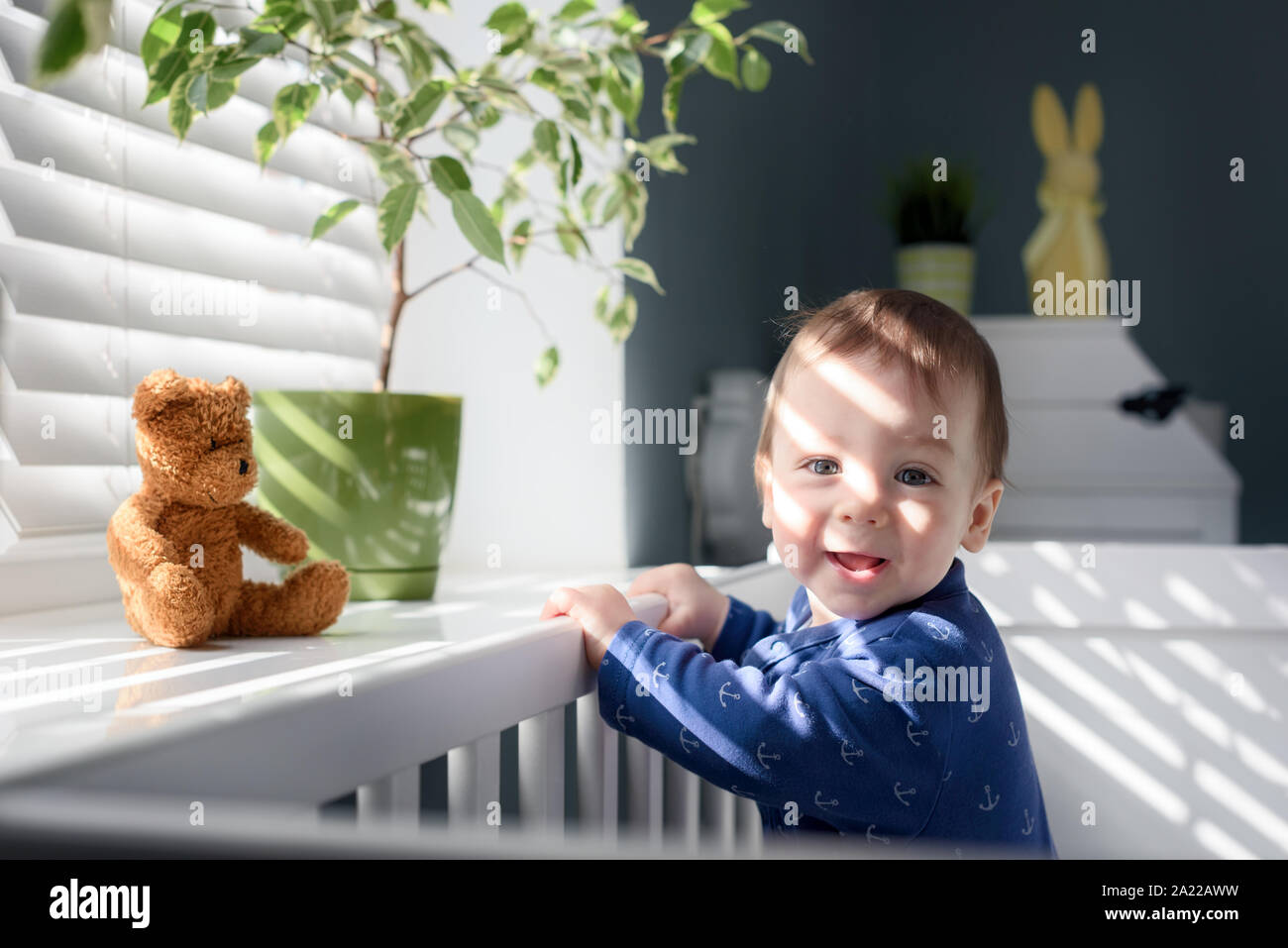 Glückliches Kind in der Nähe der Fenster auf weißen Bett in seinem Zimmer Stockfoto