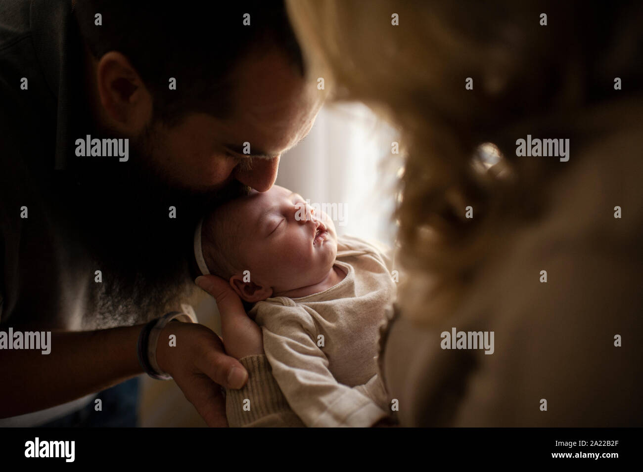 Vater küssen Schlafen neugeborene Töchter Kopf im Arm der Mutter Stockfoto