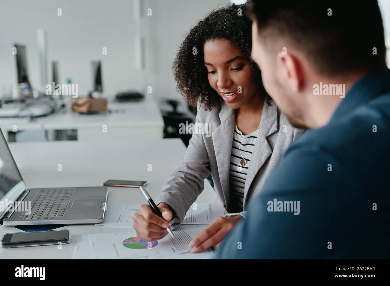 Nahaufnahme der jungen weiblichen Executive diskutieren Business Plan zu ihrer Kollegin mit Diagramm und Tabelle auf Schreibtisch Stockfoto